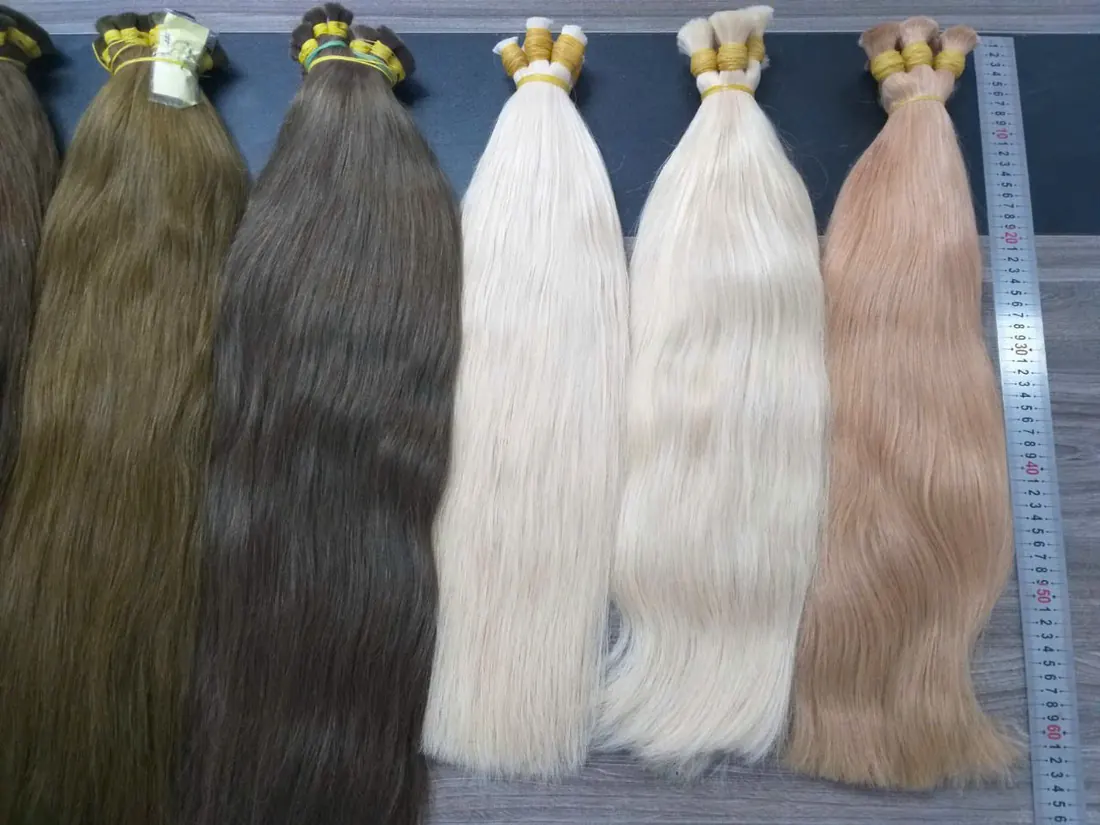 Raw hair bundles in brown, platinum and rose blonde measured against a ruler
