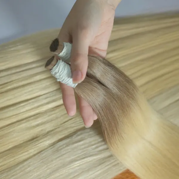 Ash-rooted blonde bundles held over a table of blonde hair